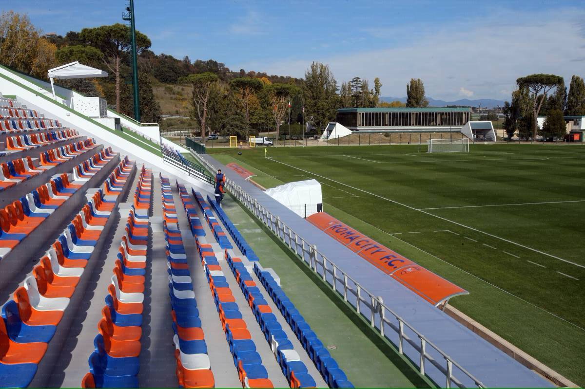 Panchina in fossa, porte da calcio e tribune presso l'Athletic Center di Riano, Roma.